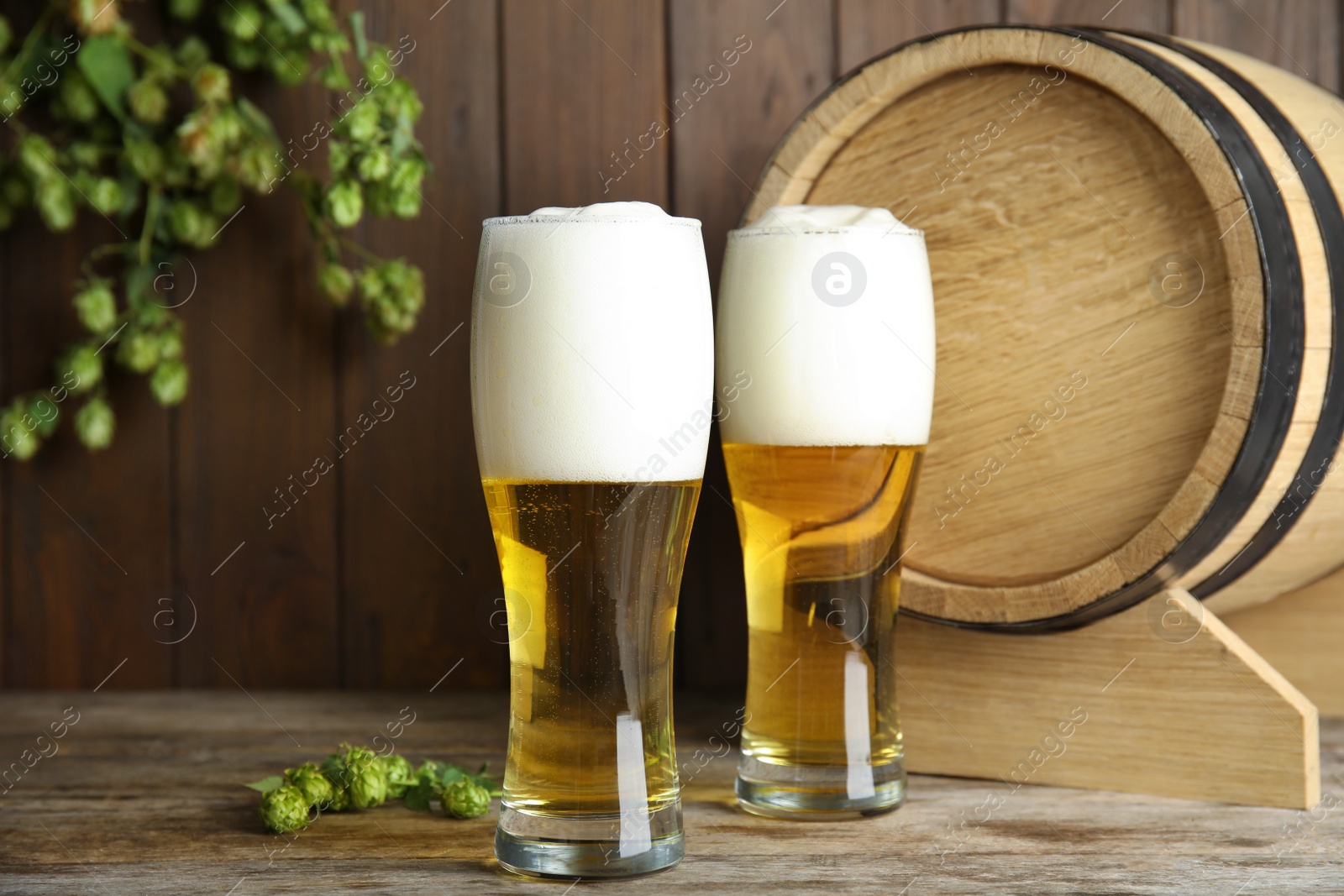 Photo of Composition with tasty beer and fresh green hops on wooden table