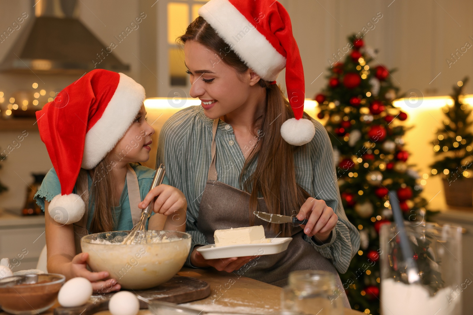 Photo of Mother with her cute little daughter making dough for Christmas cookies in kitchen