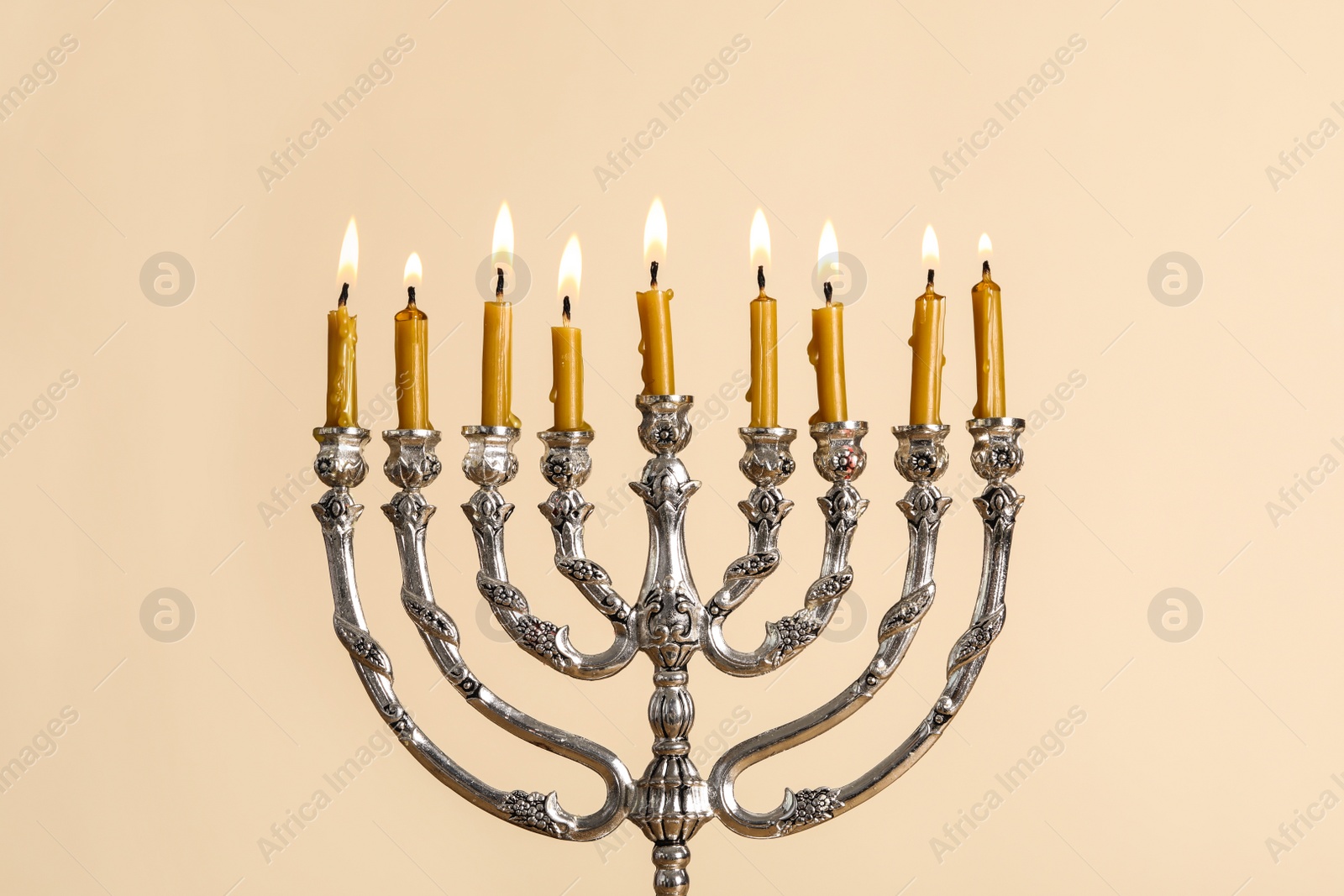 Photo of Silver menorah with burning candles on beige background. Hanukkah celebration
