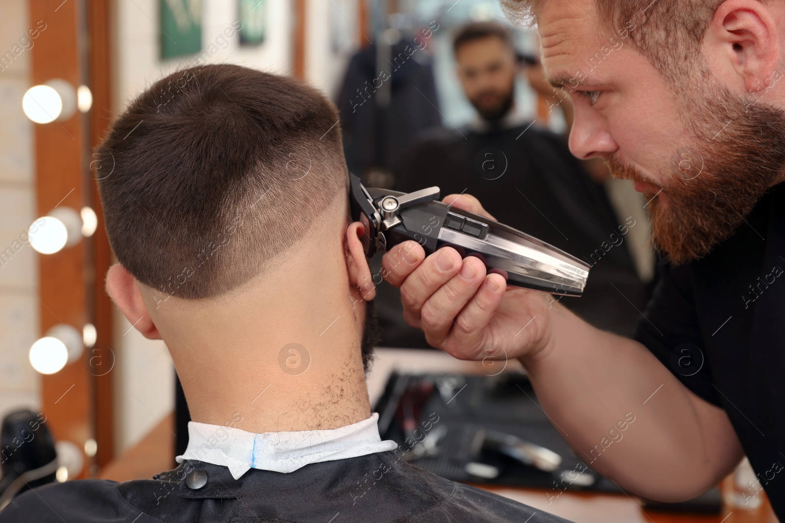 Photo of Professional hairdresser working with client in barbershop, closeup