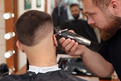 Professional hairdresser working with client in barbershop, closeup