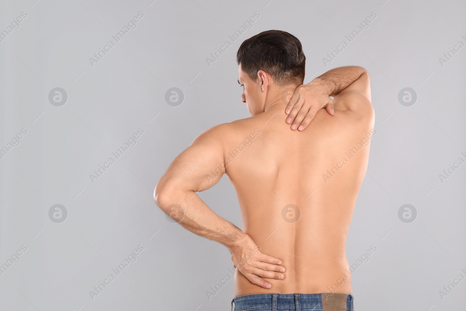 Photo of Man suffering from pain in back on light grey background. Visiting orthopedist