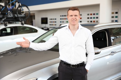 Portrait of young salesman in car dealership