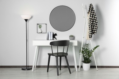 Photo of Stylish room interior with round mirror on white wall over desk