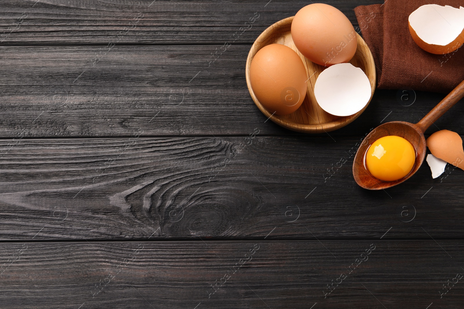 Photo of Chicken eggs on black wooden table, flat lay. Space for text