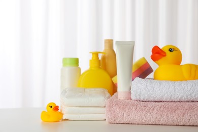 Towels, rubber ducks and baby care products on white table indoors