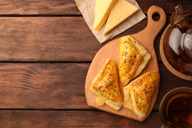 Photo of Fresh delicious puff pastry served with cheese and tea on wooden table, flat lay. Space for text