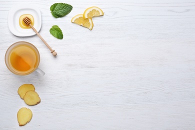 Composition with cup of lemon tea and ginger on wooden background, top view. Space for text