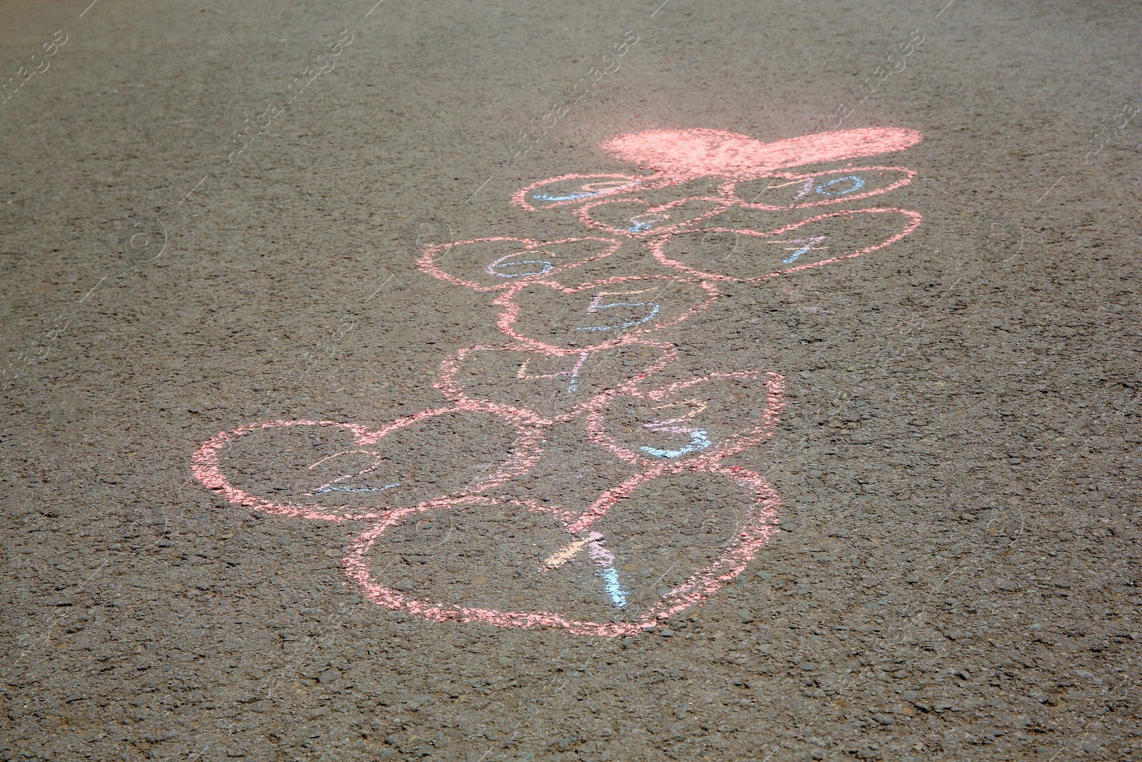 Photo of Hopscotch drawn with colorful chalk on asphalt outdoors, closeup