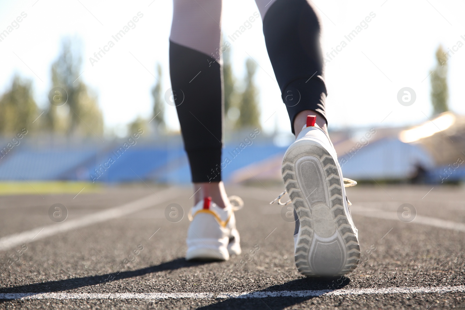 Photo of Sporty woman running at stadium on sunny morning, focus on legs