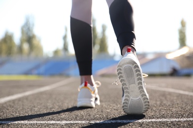 Photo of Sporty woman running at stadium on sunny morning, focus on legs
