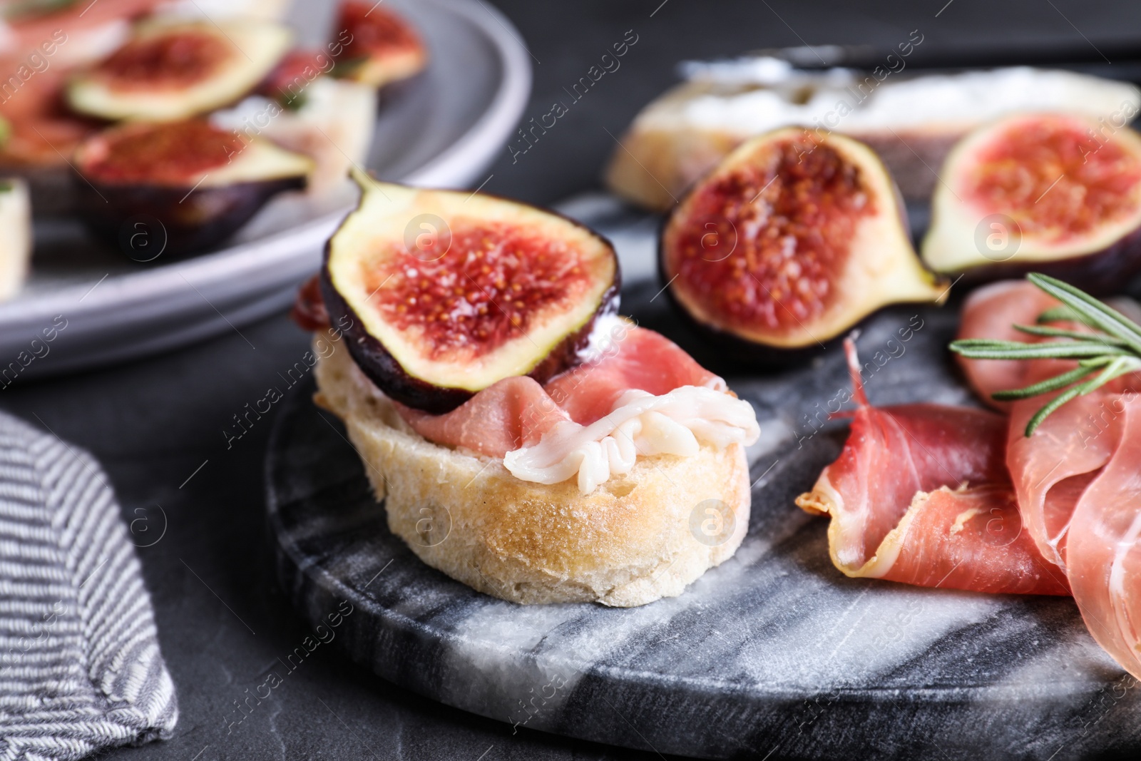Photo of Sandwich with ripe fig, cream cheese and prosciutto served on black table, closeup