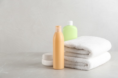 Photo of Fresh towels and toiletries on light grey marble table. Space for text