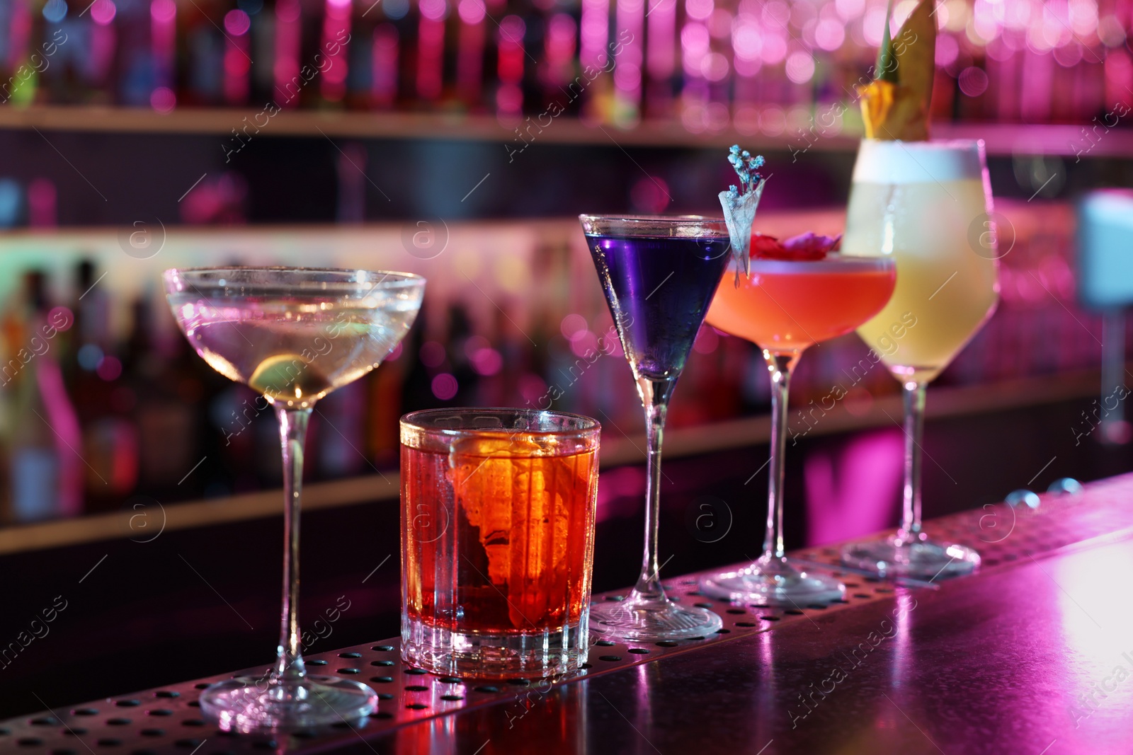 Photo of Different fresh alcoholic cocktails on counter in bar