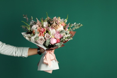 Photo of Man holding beautiful flower bouquet on green background, closeup view. Space for text