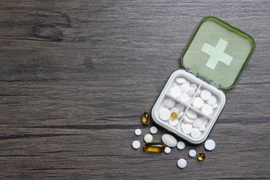 Photo of Pill box with medicaments on wooden table, flat lay. Space for text