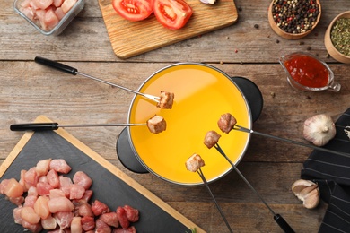 Flat lay composition with fondue pot and meat on wooden table