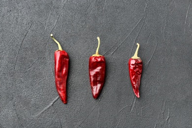 Dry chili peppers on grey background, top view