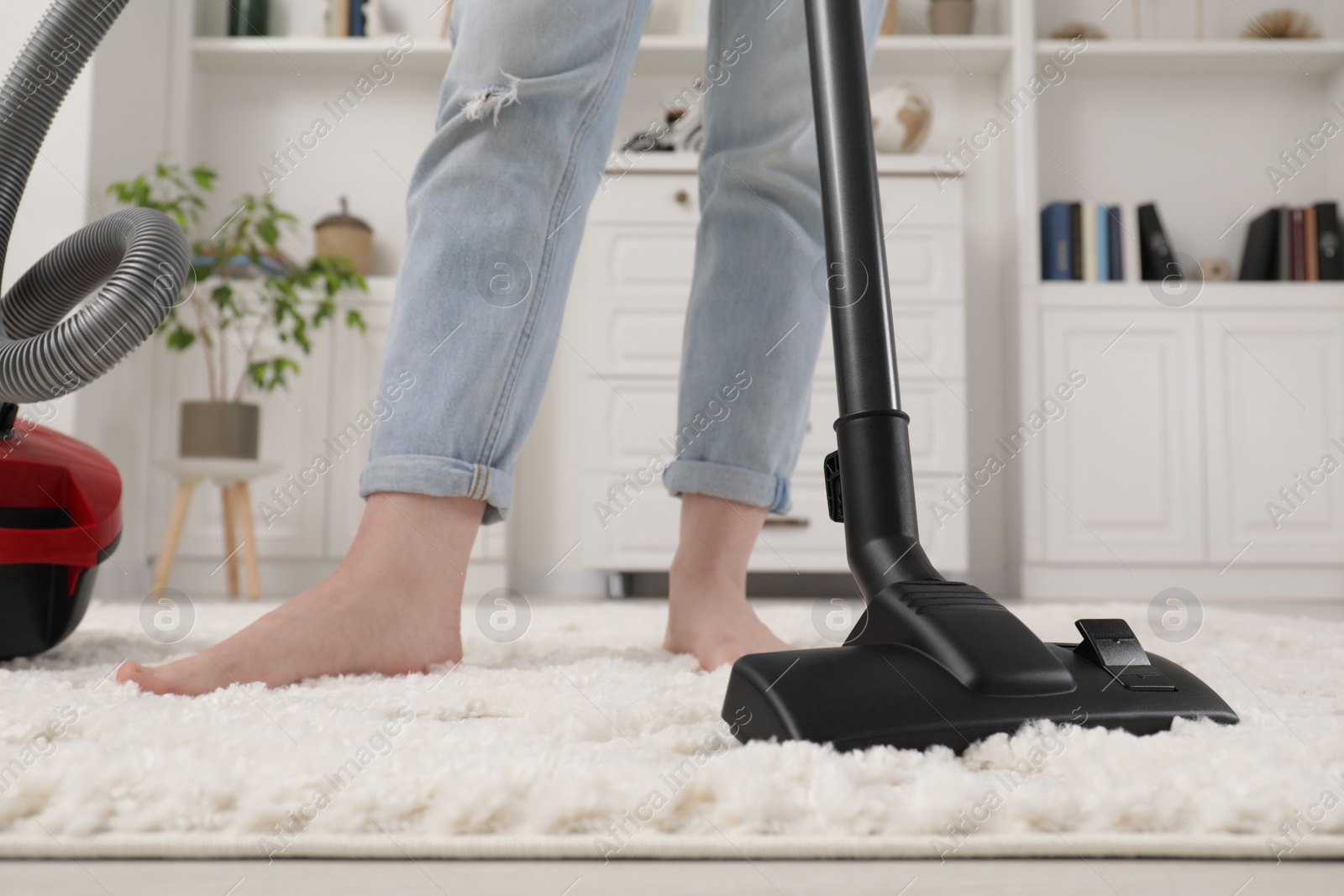 Photo of Woman cleaning carpet with vacuum cleaner at home, closeup