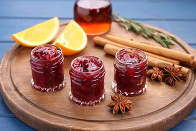 Cranberry sauce in jars and ingredients on blue wooden table, closeup