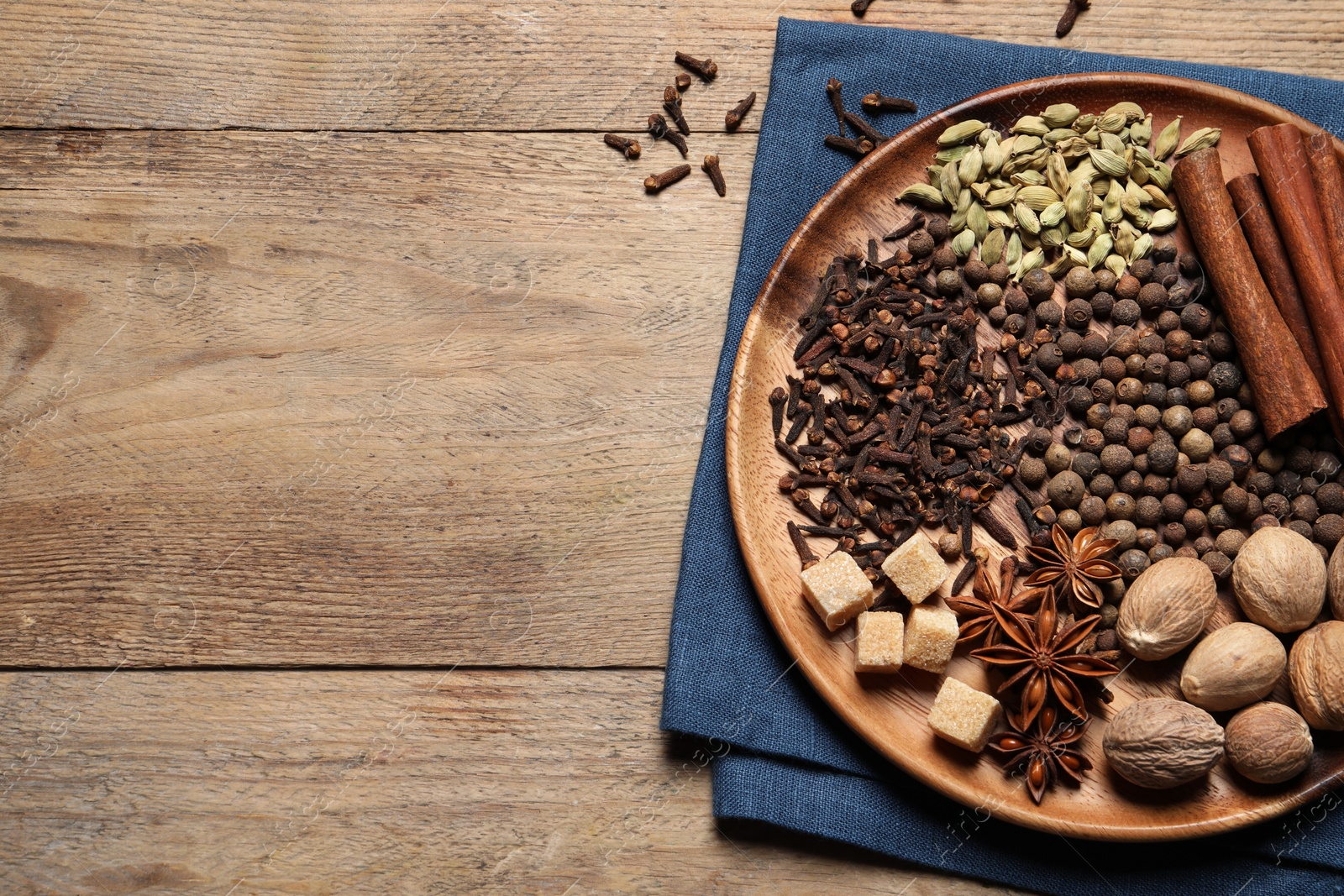 Photo of Different spices and nuts on wooden table, top view. Space for text