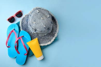 Photo of Flat lay composition with sunscreen and different beach accessories on light blue background. Space for text
