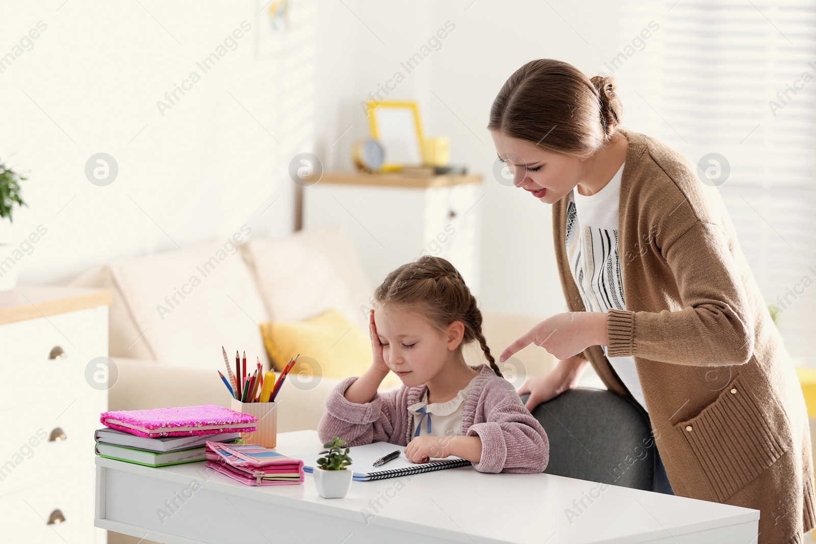 Photo of Mother scolding her daughter while helping with homework indoors