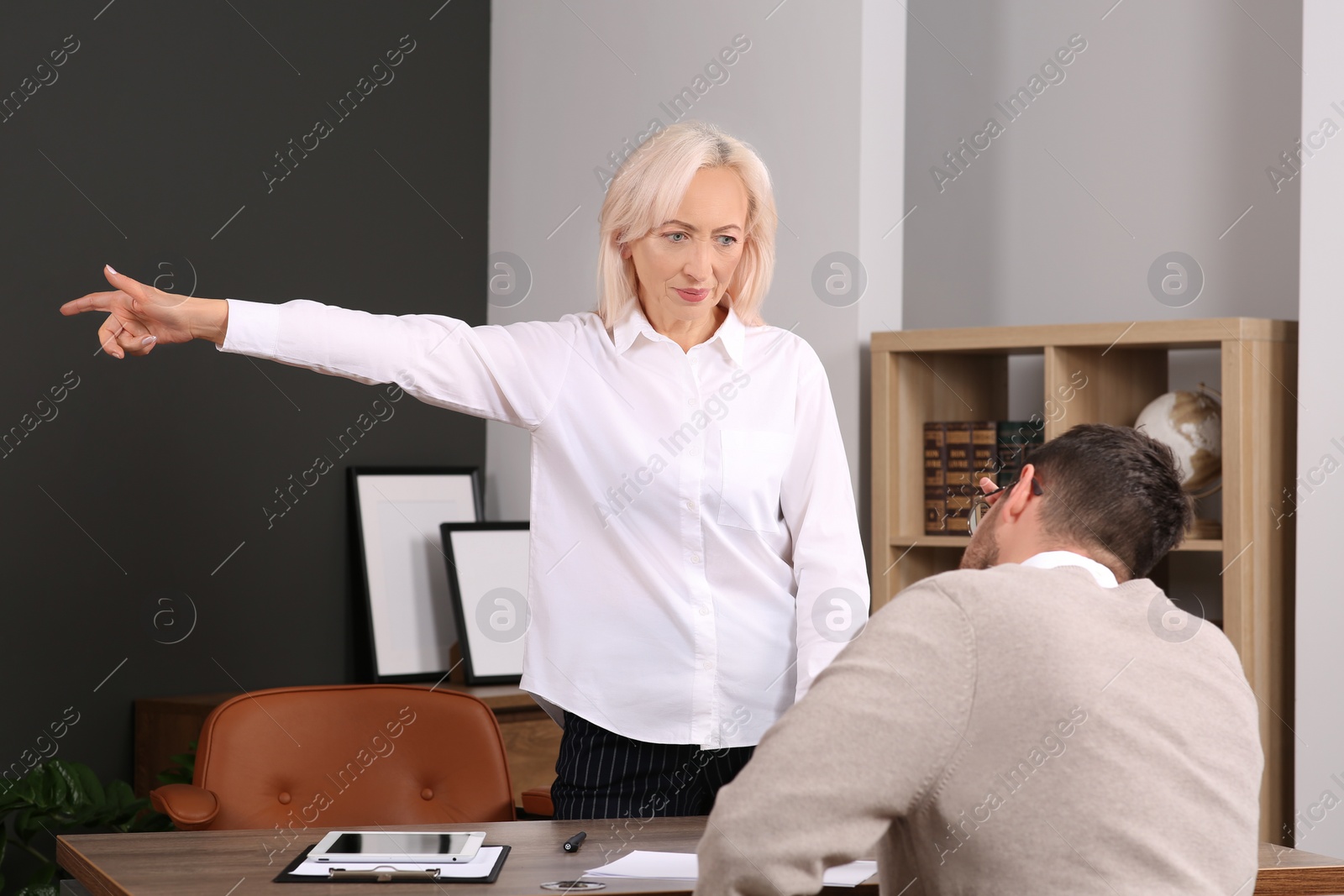 Photo of Angry boss pointing to get out and stressed employee at wooden table in office
