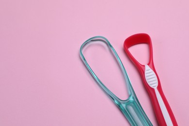 Photo of Tongue cleaners on pink background, flat lay. Space for text