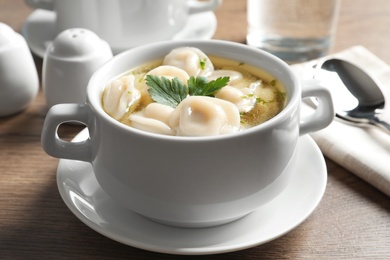 Bowl of tasty dumplings in broth served on wooden table