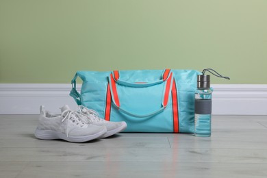 Photo of Bag with different sports equipment on wooden floor indoors