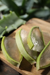 Slices of fresh aloe vera leaves with gel on wooden table, closeup
