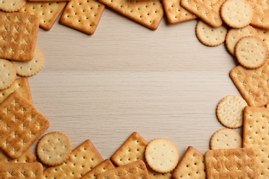 Frame of delicious crackers on wooden table, flat lay. Space for text