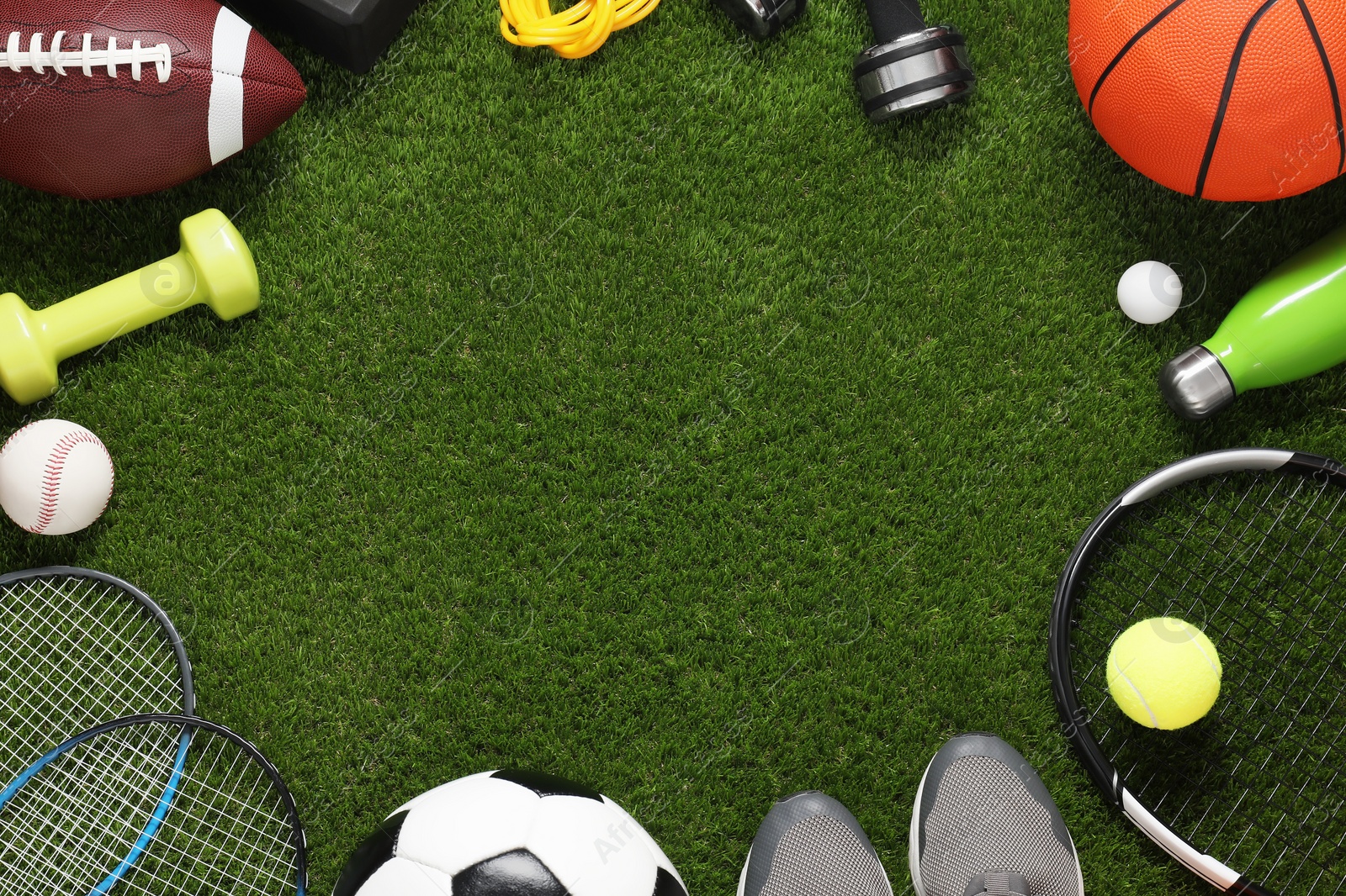 Photo of Frame of different sport tools on green grass, flat lay. Space for text