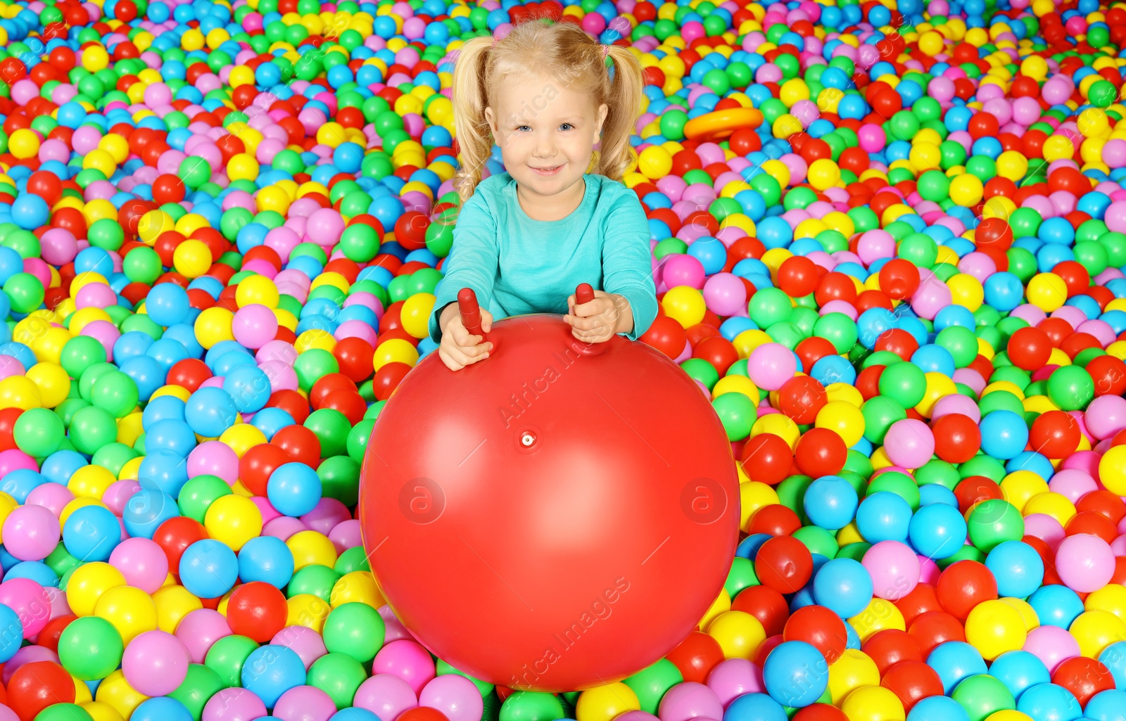 Photo of Cute child playing in ball pit indoors