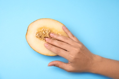 Photo of Young woman touching half of melon on blue background, top view. Sex concept