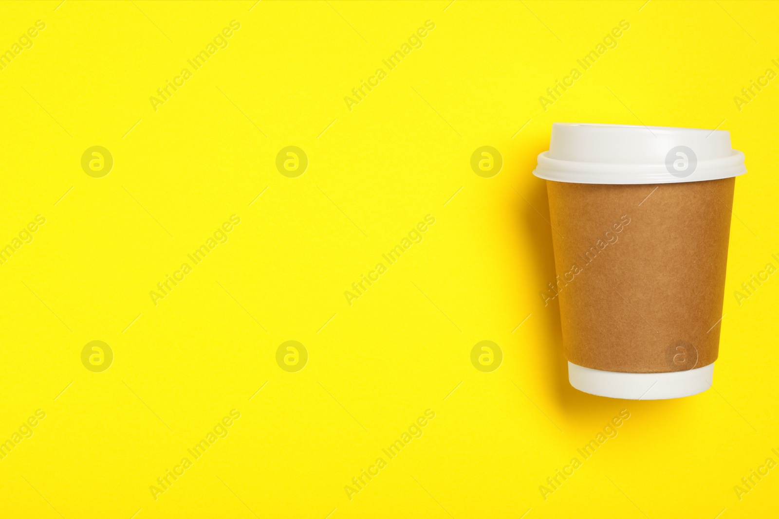 Photo of Takeaway paper coffee cup on yellow background, top view. Space for text