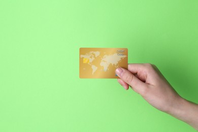 Photo of Woman holding credit card on light green background, closeup