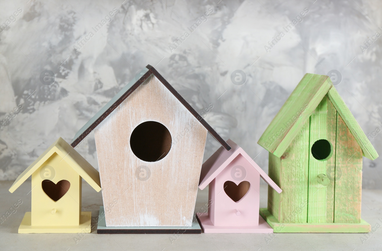 Photo of Collection of handmade bird houses on light grey stone background