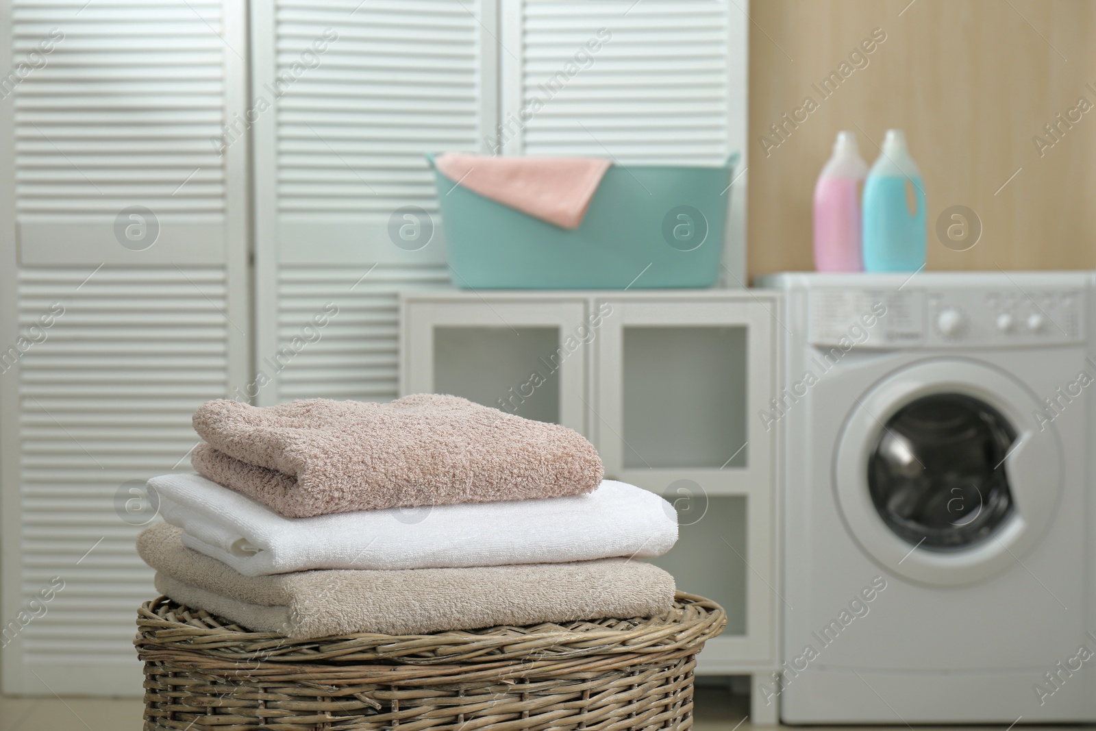 Photo of Fresh towels on wicker basket in laundry room