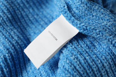 Photo of Clothing label with material content on blue sweater, closeup view