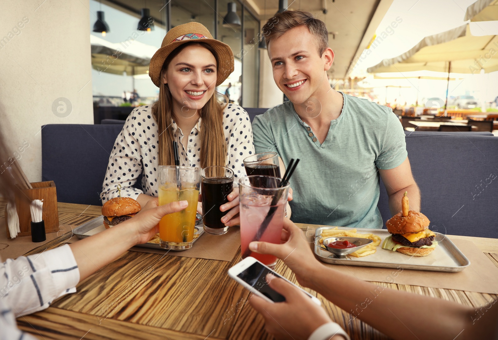 Photo of Young people with burgers in street cafe