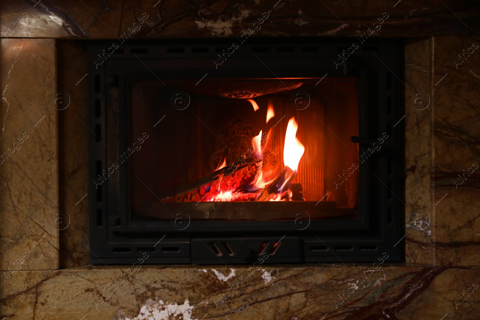 Photo of Fireplace with burning wood in darkness indoors