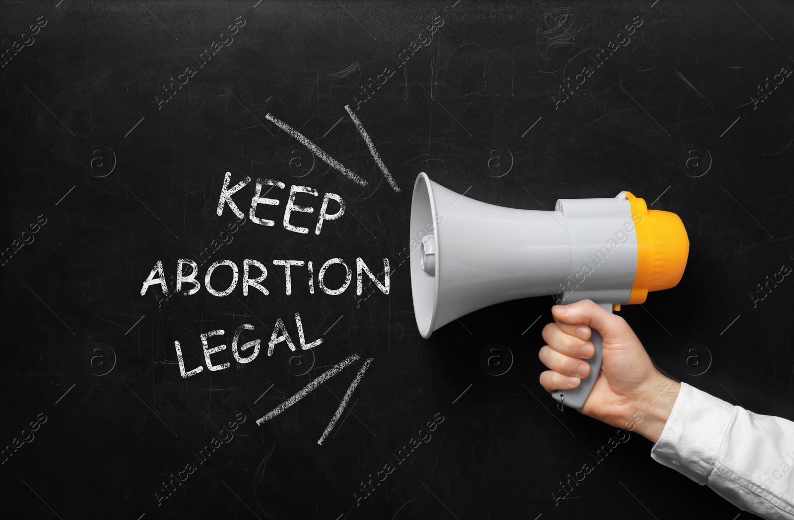 Image of Man with megaphone involved in reproductive rights protest, closeup. Slogan Keep Abortion Legal on black chalkboard