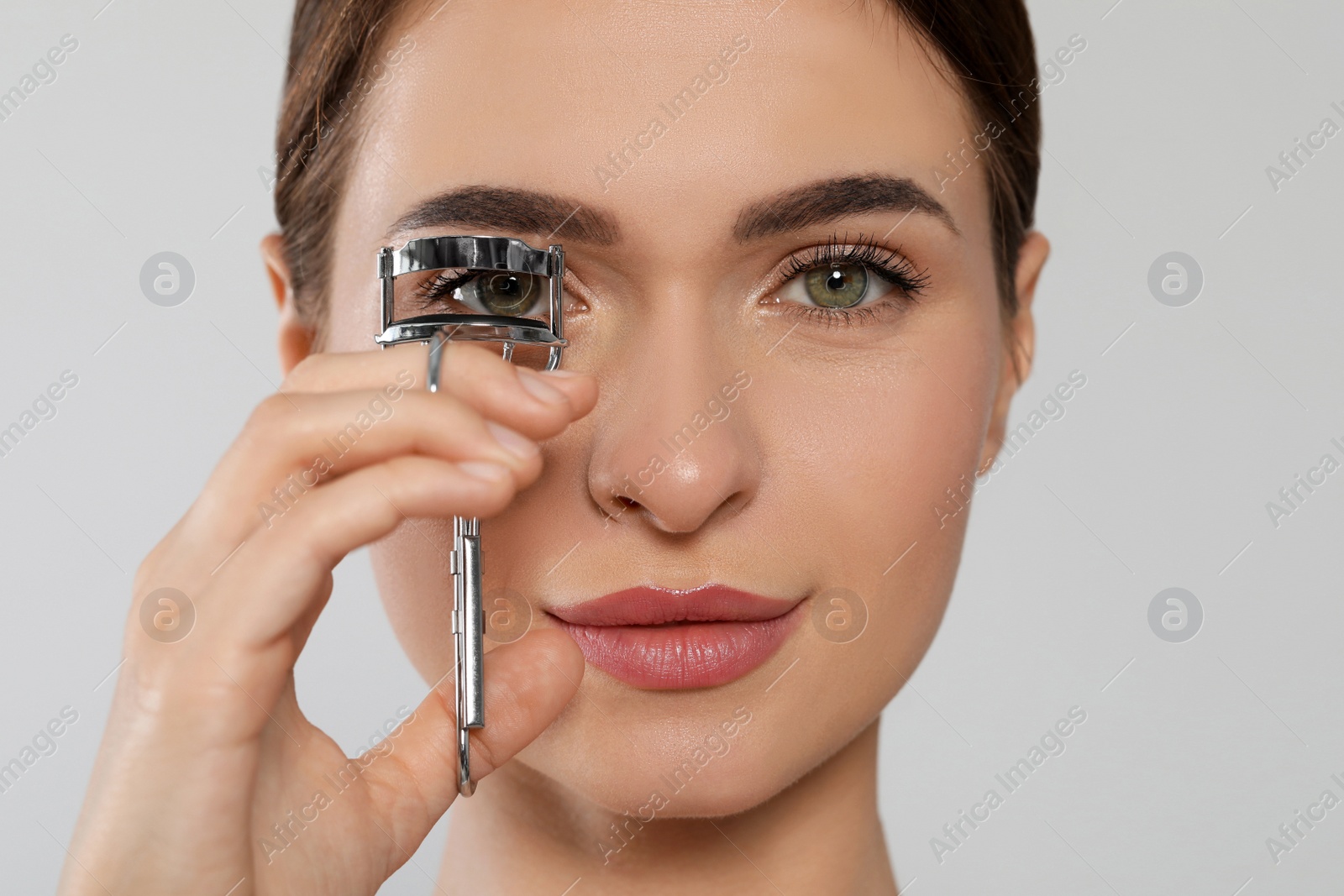 Photo of Woman using eyelash curler on white background, closeup