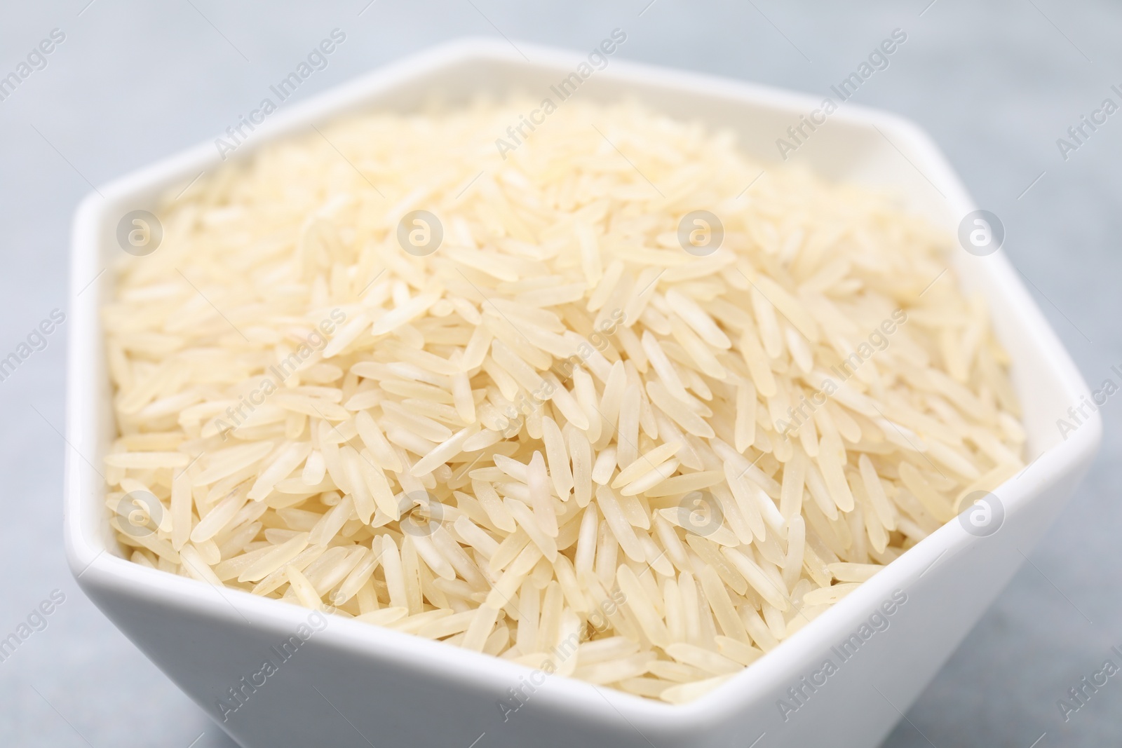 Photo of Raw rice in bowl on table, closeup