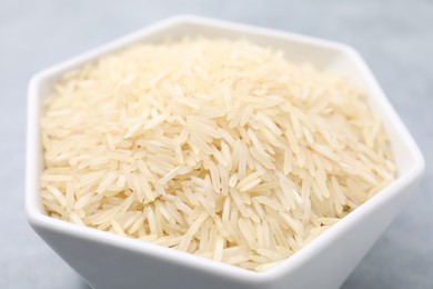 Raw rice in bowl on table, closeup