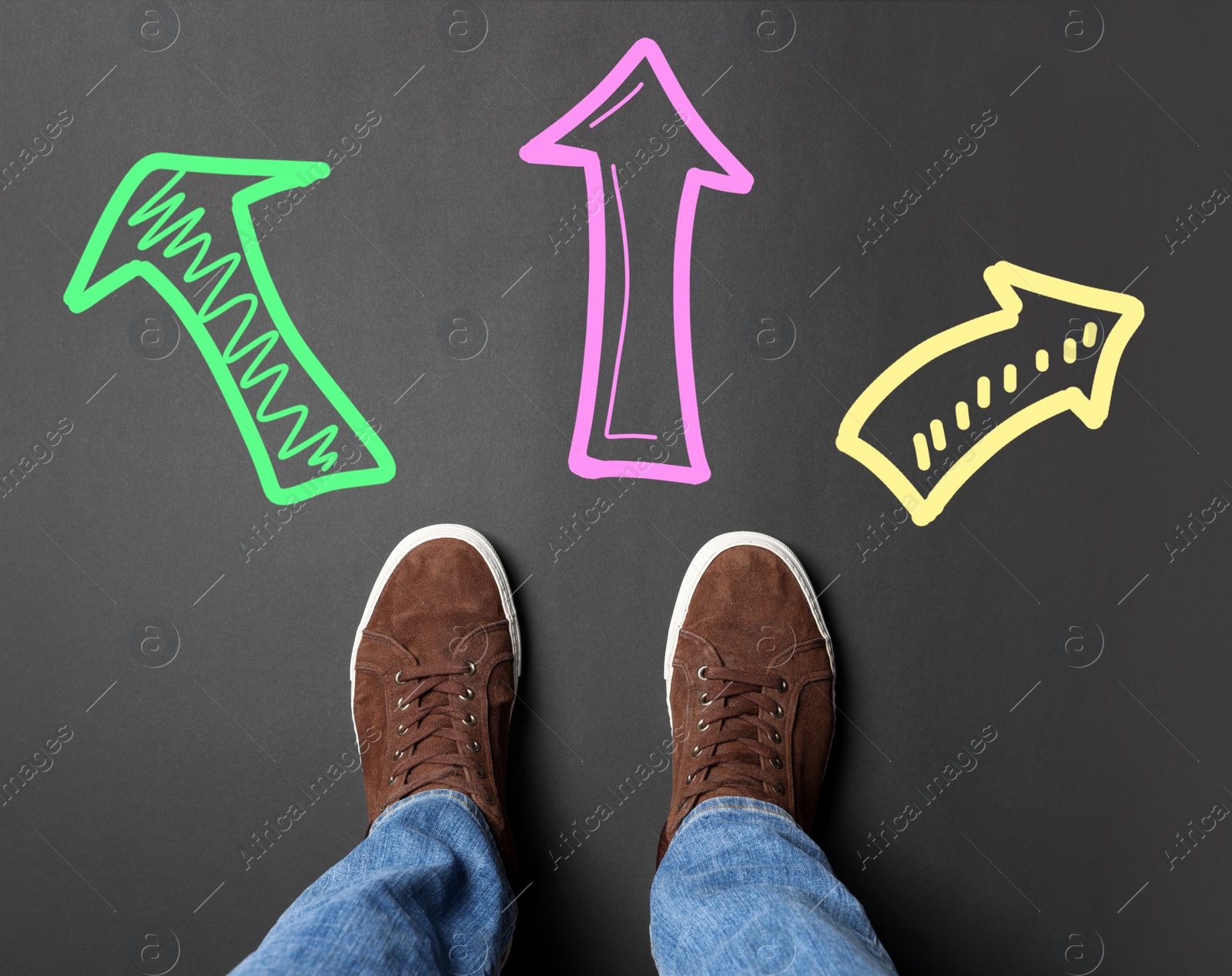 Image of Choosing future profession. Man standing in front of drawn signs on black background, top view. Arrows pointing in different directions symbolizing diversity of opportunities