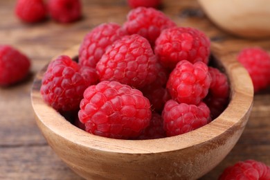 Photo of Tasty ripe raspberries in bowl on wooden table, closeup