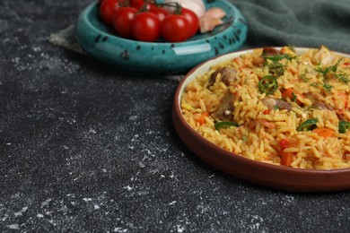 Photo of Delicious pilaf with meat and ingredients on black textured table. Space for text